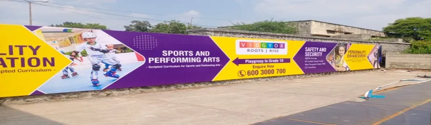 Long campus boundary wall wrapped in a purple VIBGYOR schools banner